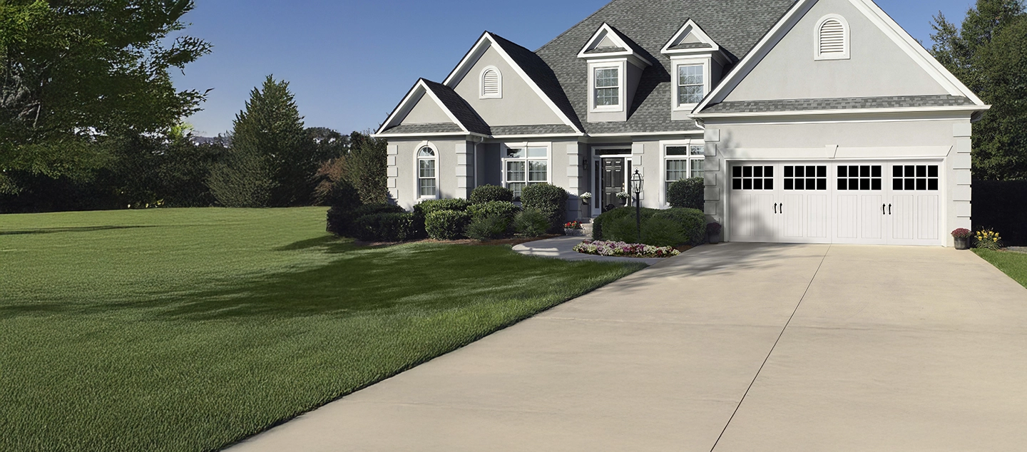 Stone house with triple wood garage doors and a flower bed.